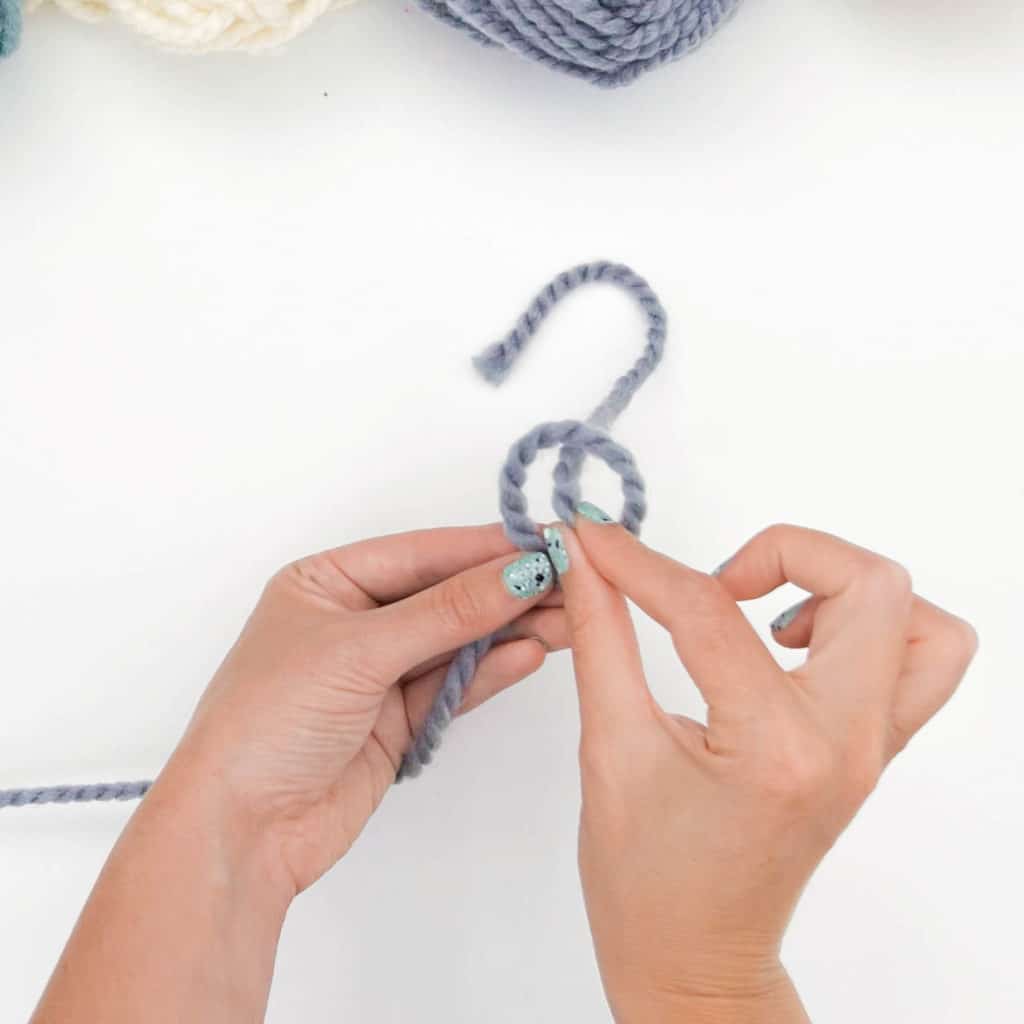 How to Tie a Slip Knot - Step 4.
The yarn tail is brought behind and up through the loop.