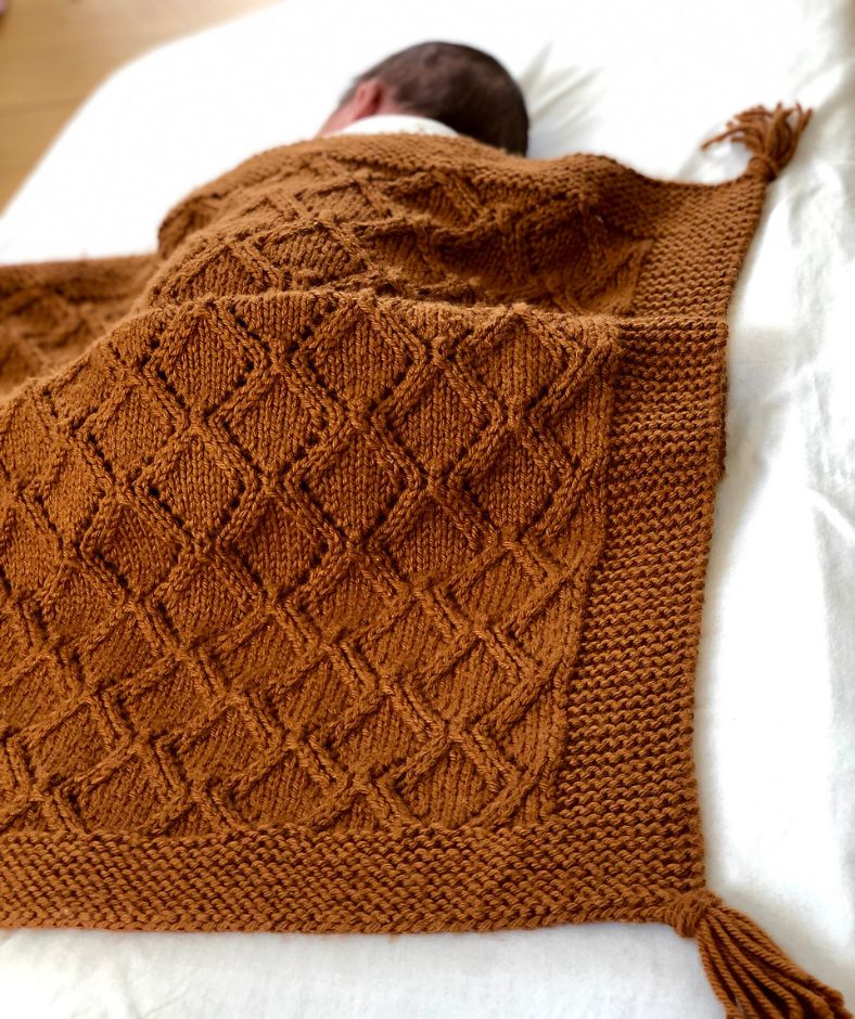 Baby Blanket Knit Patterns - Marius Baby Blanket in caramel brown draped over a baby while sleeping