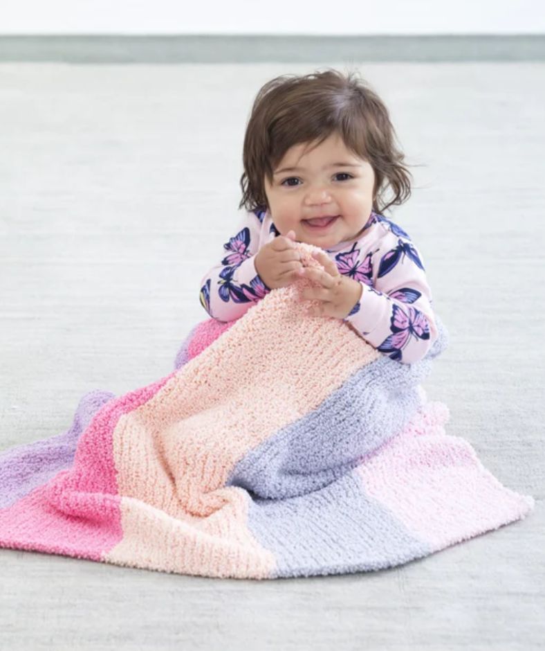 Baby Blanket Knit Patterns - a little one holds on to a Plush Striped Baby Afghan while sitting on the floor