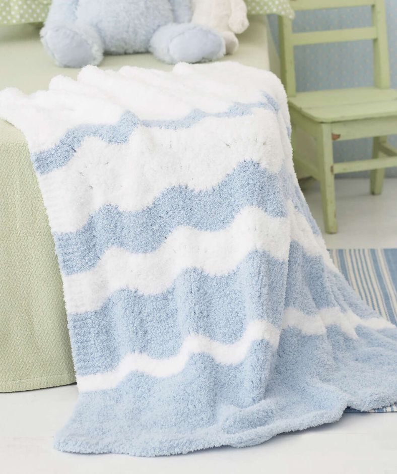 Baby Blanket Knit Patterns - Fading Waves blanket in blue and white draped over a couch, touching the floor