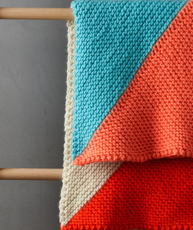 Baby Blanket Knit Patterns  - blue, red, beige Four Points Baby Blanket hanging on a towel ladder