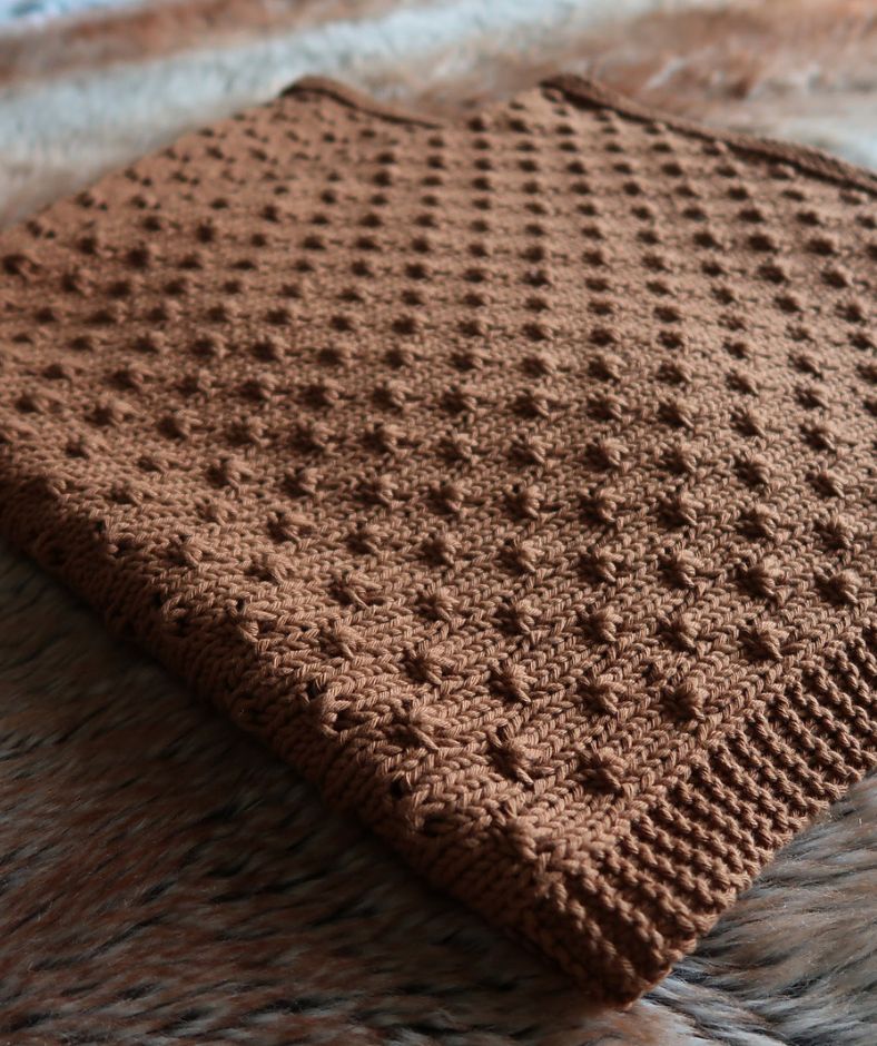 Baby Blanket Knit Patterns - brown Knot Stitch Baby Blanket folded on a rug