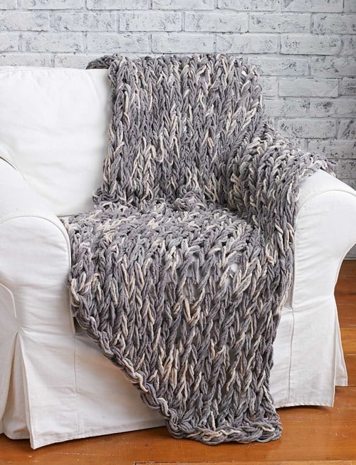 Photo of an arm knit blanket draped on a chair.