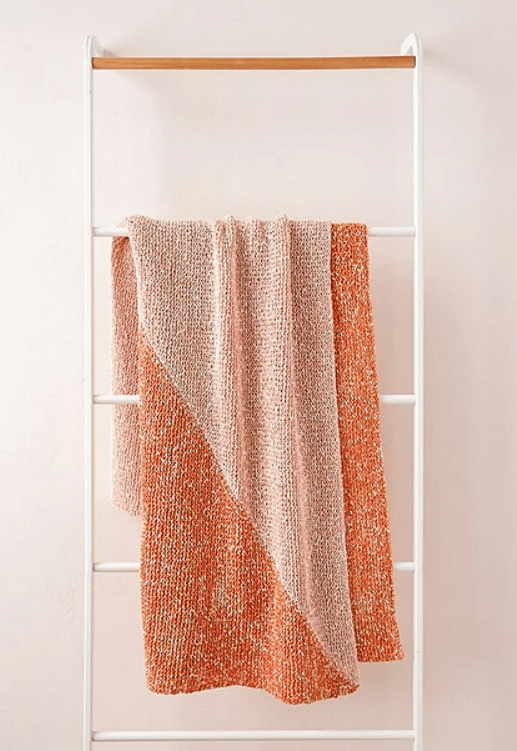 Image of a knit blanket draped over a towel rack. Another pattern that is part of the list of free blanket knitting patterns.