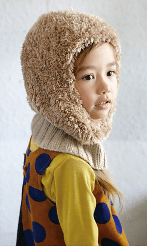 An image of a child wearing a fuzzy balaclava. This is the finished version of the 214W-10 Teti Cap.