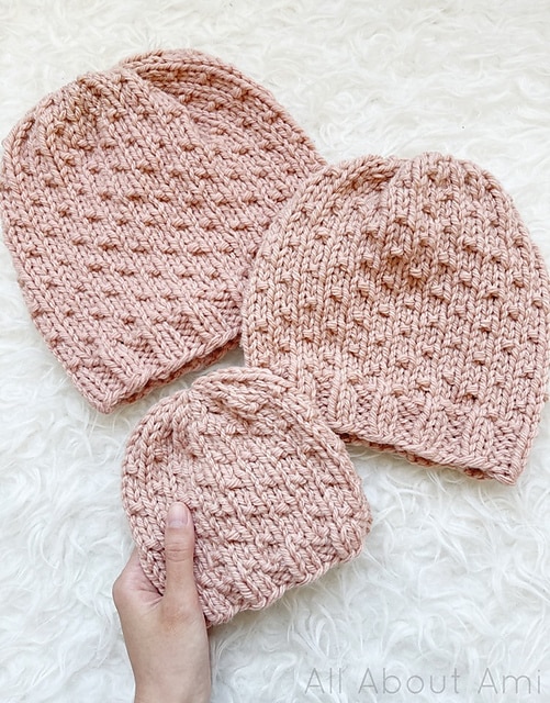 This photo shows a woman holding a beanie flat to show off this easy knit beanie pattern.