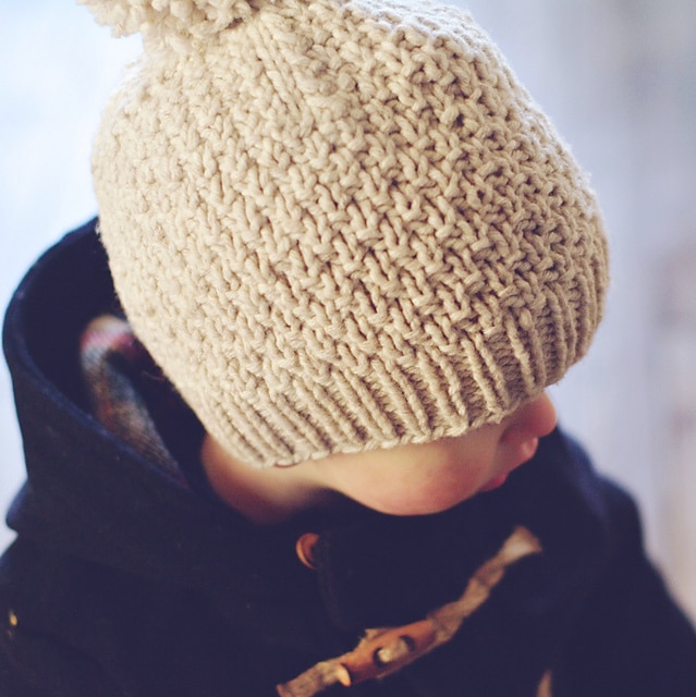 A child wearing the Beloved Aran knitted beanie to show off the unique stitches in this knit beanie pattern.
