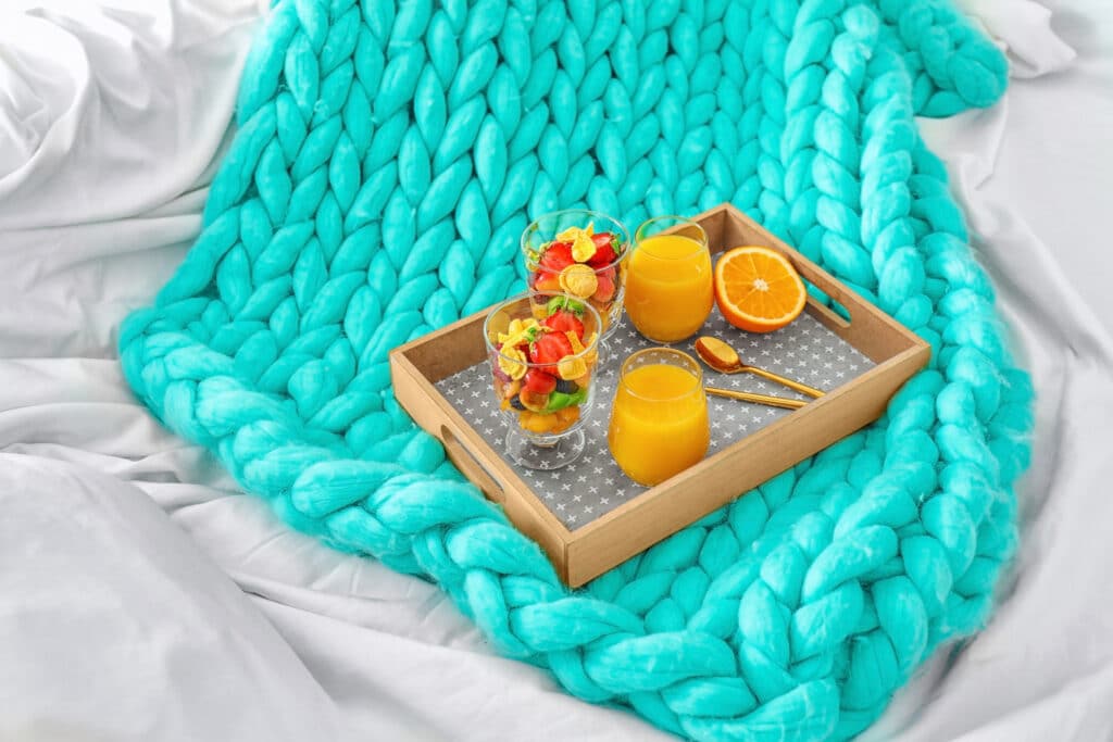 Image showing a knitted blanket with fruit salad and juices in a tray. This is simply an image to help showcase the free blanket knitting patterns.