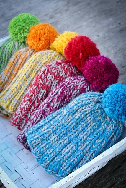 A basket of beanies in different colors to show off the look of the easy knit beanie pattern.