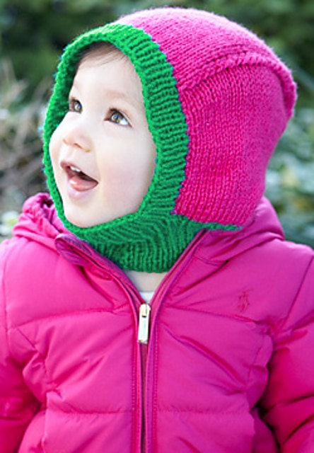 A cute, smiling baby wearing a finished version of the Babyhood balaclava pattern.