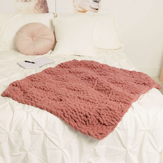 Image of a knitted basketweave blanket on a white bed. This is the finished image of a pattern showing how to make a chunky knit blanket.