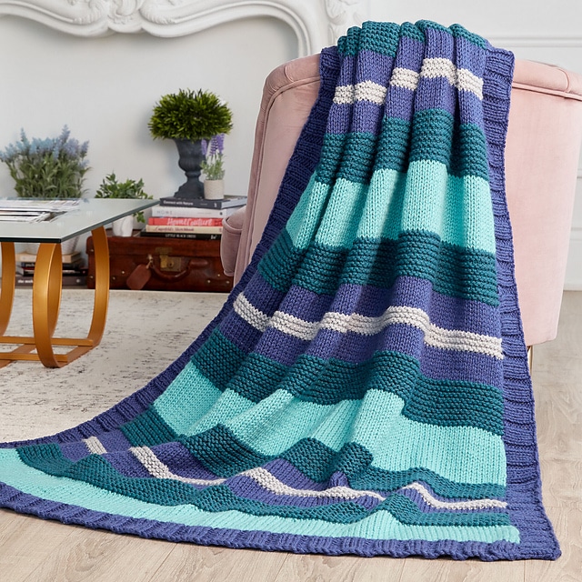 An image of a large blanket that drapes over the chair and onto the floor. This photo is another part of the "free blanket knitting patterns" list.