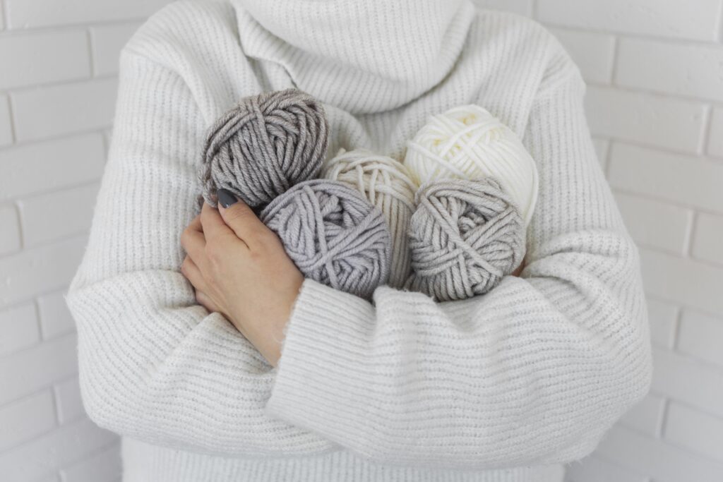 A arms holding balls of chunky yarn.