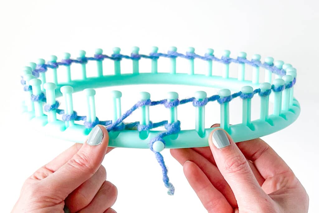 Image showing how to create the knit stitch in loom knitting. It is also called the "E-Wrap" knit stitch.