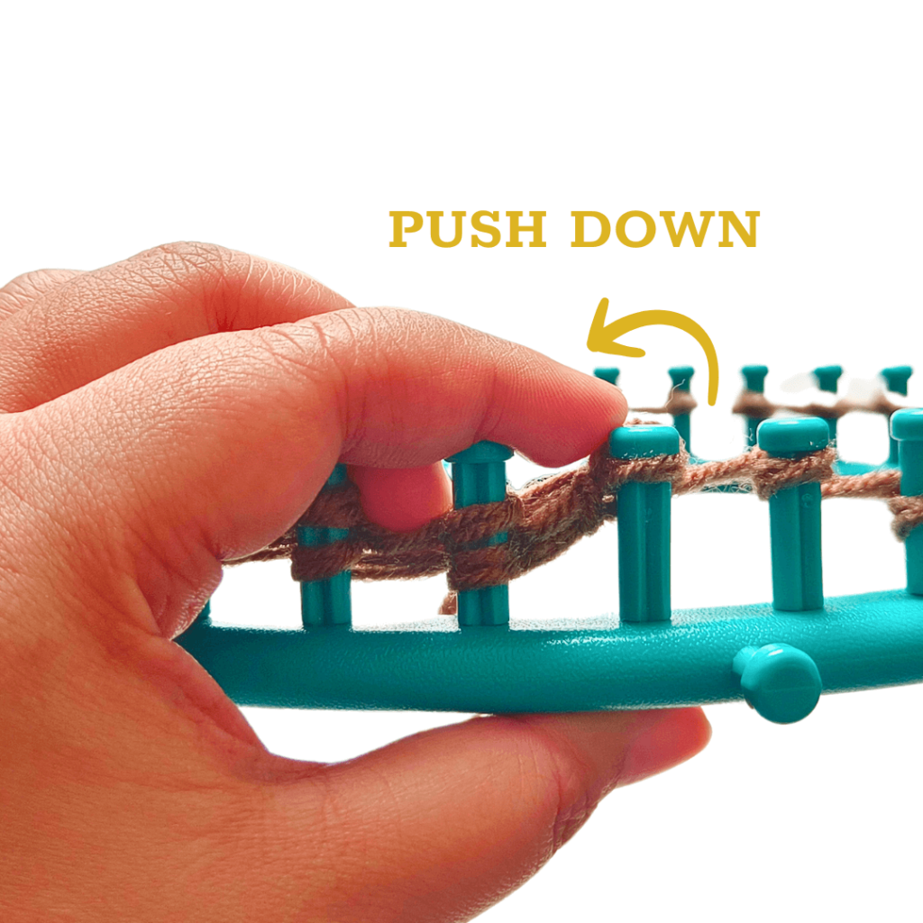 Drop the stitch behind the peg and push the stitch down. 

Now you have a knit stitch. Repeat this on all of the e-wrap knit stitch pegs!