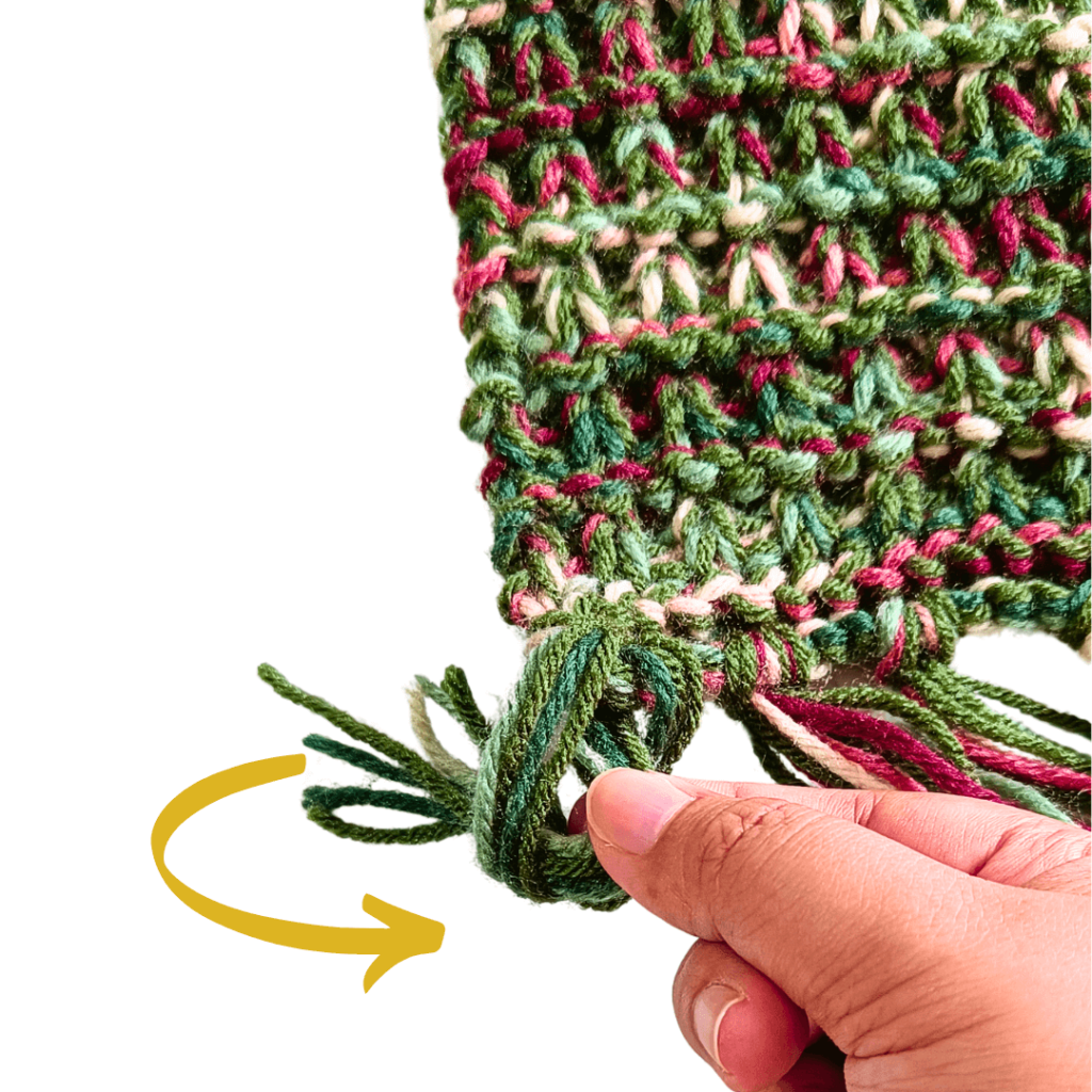 Remove your stitch marker or crochet hook and open the loop.

Pull the other half of the fringe through the loop.