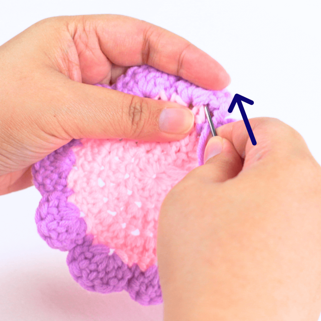 Take your yarn tail and thread it through the darning needle. Now go in between the loops of the first sc that you just slip stitched in.