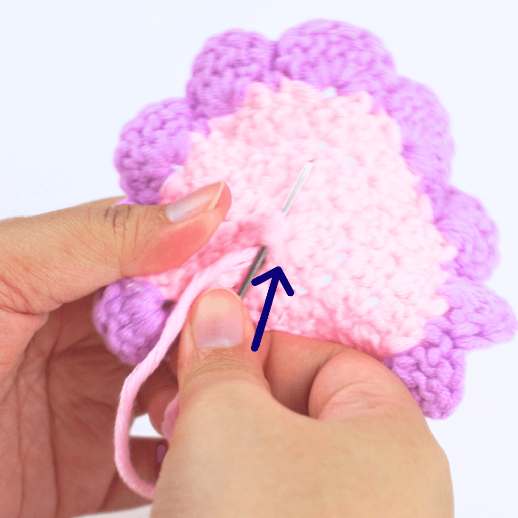Hide the yarn tail in the middle of the flower by weaving it through the magic ring. Part 1.