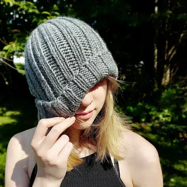 A girl wearing a grey ribbed knit beanie under the sun