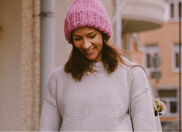 A smiling woman wearing a super chunky pink beanie