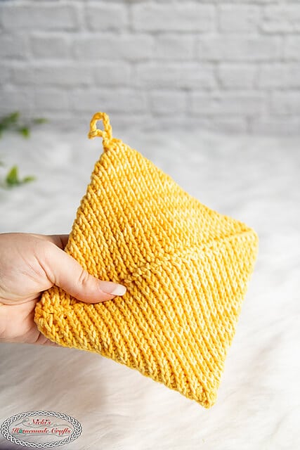A thick, yellow pot holder made using the tunisian crochet stitch.