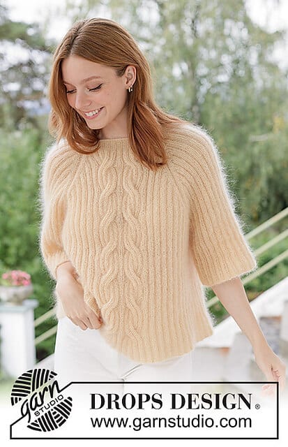 A smiling woman wearing a lightweight, cable knit sweater with 3/4 sleeves.