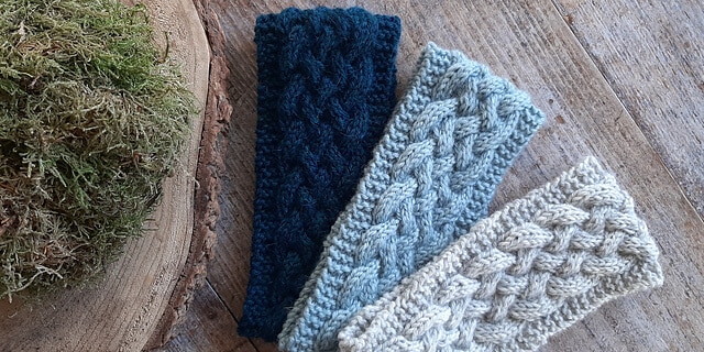 3 knitted cable headbands laaid out side by side.