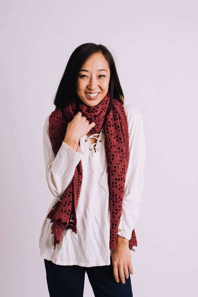 Smiling woman wearing a red crochet chevron filet crochet scarf.