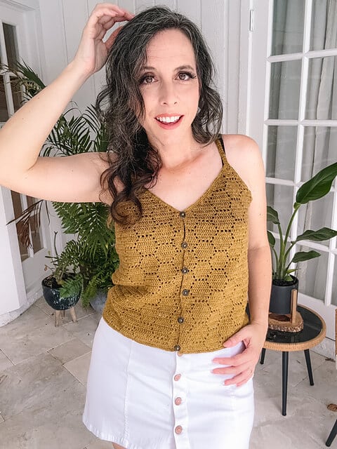 A woman wearing a honeycomb crochet tank top made with thin, light yarn.