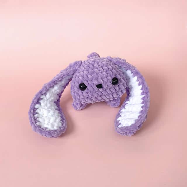 A cute amigurumi bunny pattern made with purple chenille yarn facing directly into the camera.