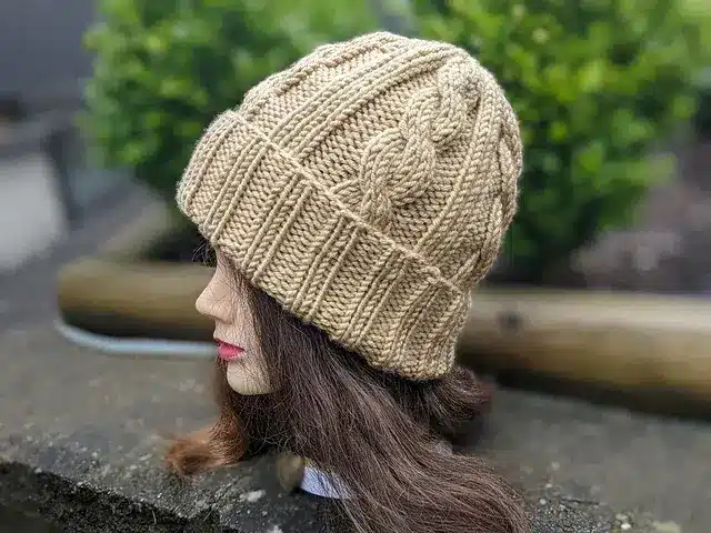 A mannequin head wearing a cable knitted beanie