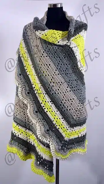 A large, comfortable crochet shawl in a green, grey, and whiterte colorway.