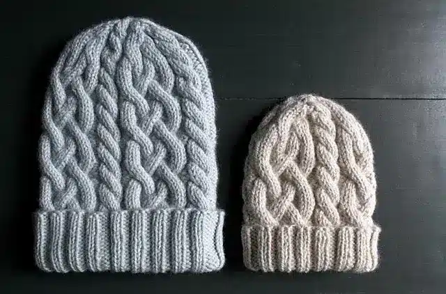 2 handmade cable knit beanies. The one on the left is for adults and the one on the left is for babies.