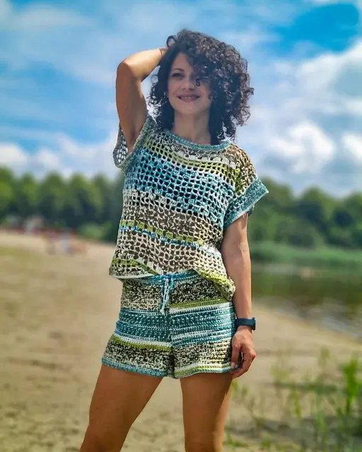 A youthful woman with curly hair wearing a crochet shorts and top set under the bright sun.