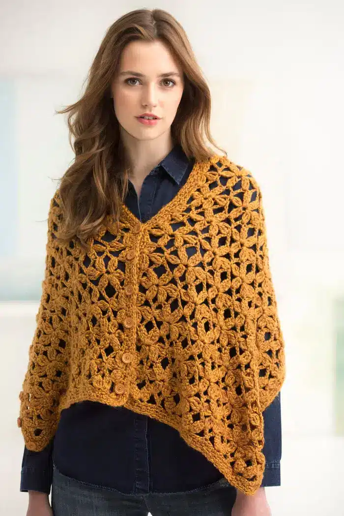 A young woman wearing a crochet shrug with floral patterns all around.