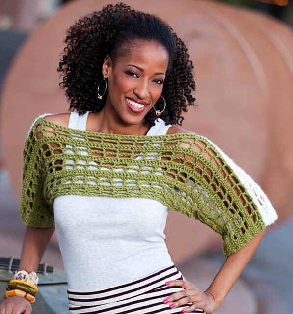 Smiling woman wearing a two-toned, green and white crochet shrug.
