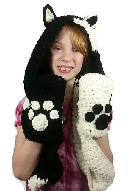 Young child wearing a loom knit hooded scarf made with black and white yarn.