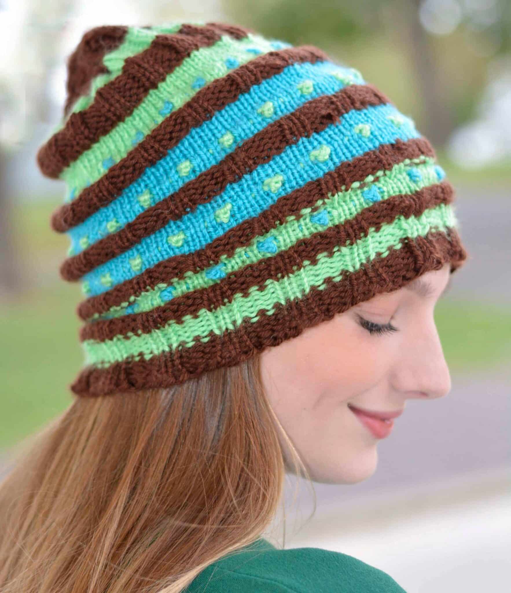 Side-profile of a woman wearing a colorful loom knit beanie.