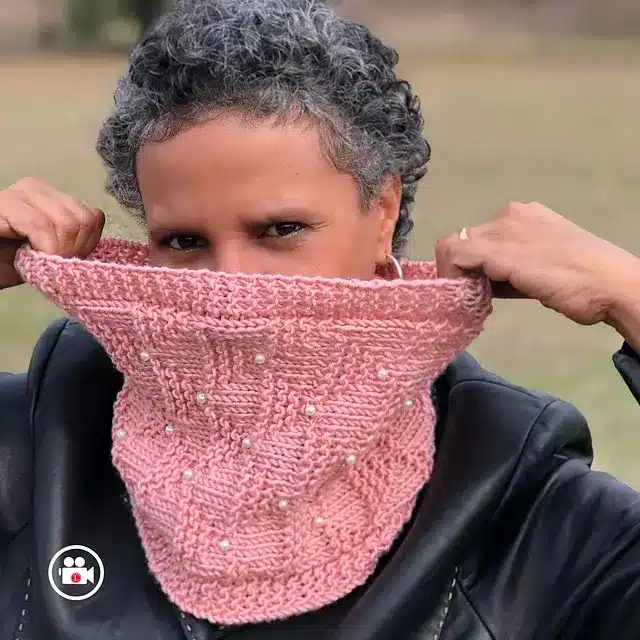 a cozy round knitting loom pattern col with small, pearl beading made with pink yarn.