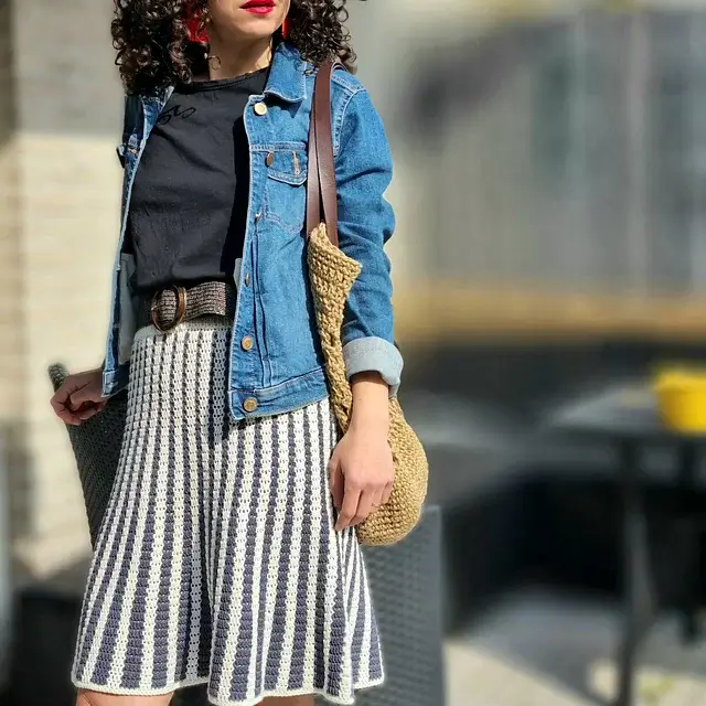 A woman wearing a flowy crochet skirt made with cream and grey yarn.