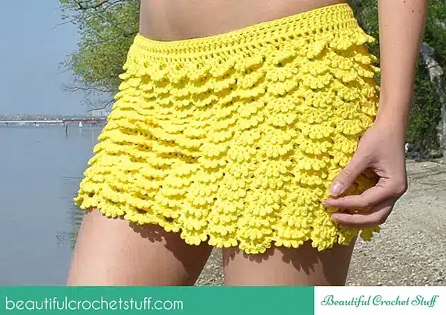 A crochet multi-layered crochet skirt made with lace details and yellow yarn.